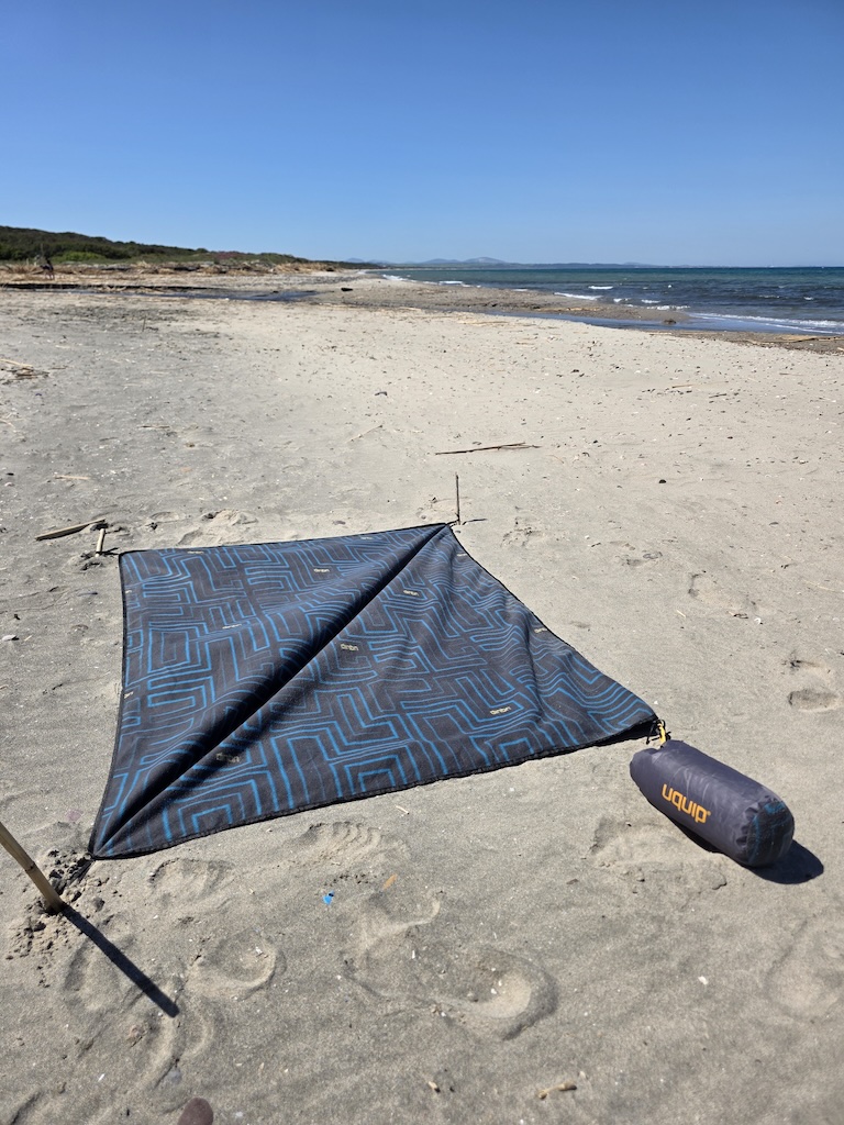 SCOTTY Picknickdecke wird am Strand mit Stecken vor dem Wind gesichert – Sardinien
